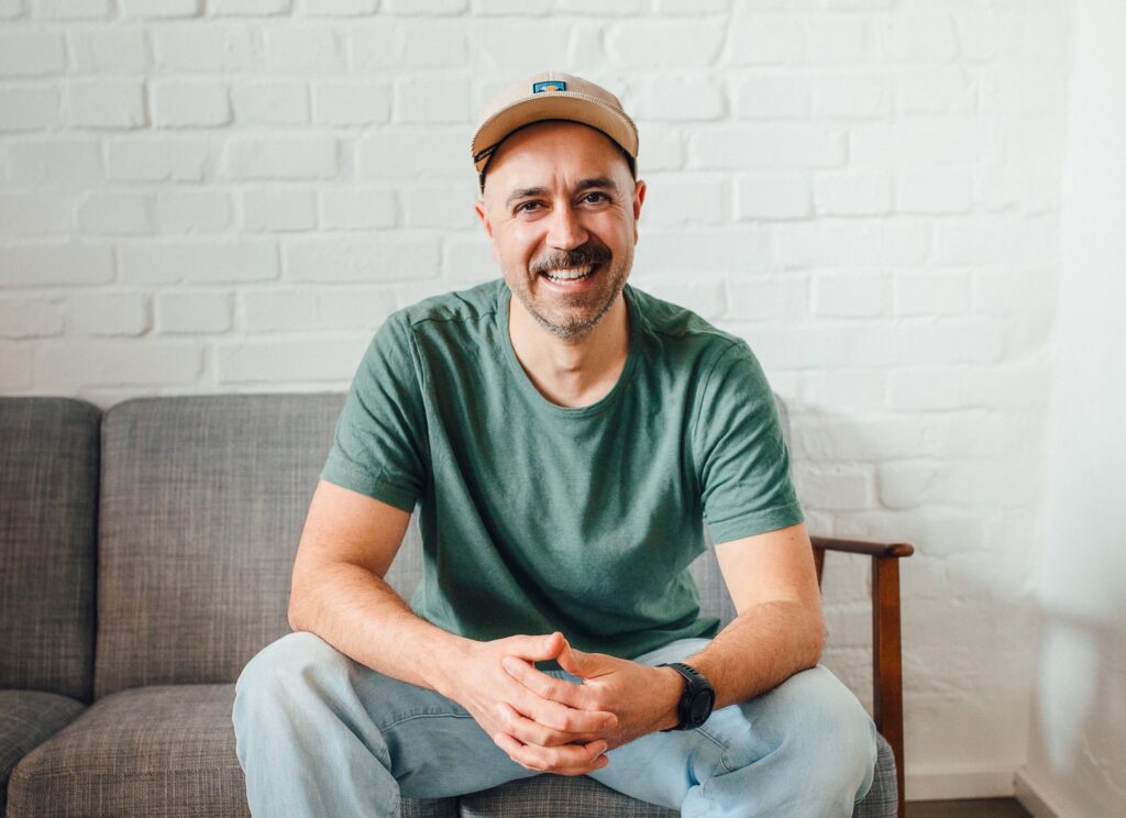 photo of a man sitting on a couch smiling