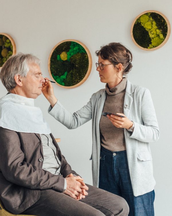 a woman putting makeup on a man's face